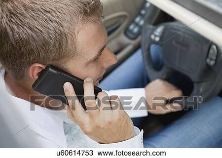 Stock Image - USA, Illinois, Metamora, man driving car and talking on phone. Fotosearch