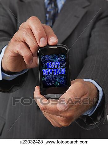 Stock Photo - USA, Illinois, Metamora, Man holding smart phone with 'Happy New Year' text on it. Fotosearch