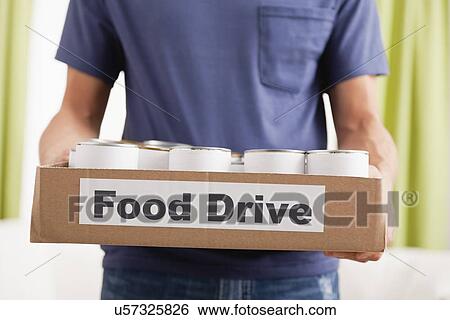 Stock Photograph - USA, Illinois, Metamora, Man holding cardboard box with canned food. Fotosearch