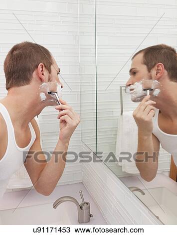 Stock Image - USA, Illinois, Metamora, Man shaving in front of mirror. Fotosearch