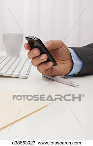 Stock Photo - USA, Illinois, Metamora, Man texting on his mobile in office. Fotosearch