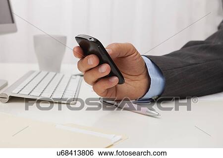 USA, Illinois, Metamora, Man texting on his mobile in office View Large Photo Image Stock Photograph - USA, Illinois, Metamora, Man texting on his mobile in office. Fotosearch