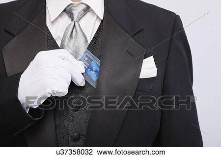 Stock Image - USA, Illinois, Metamora, Man wearing tuxedo holding card, mid section. Fotosearch