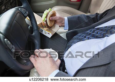 Stock Photo - USA, Illinois, Metamora, Man's hands holding burger and disposable cup with straw. Fotosearch