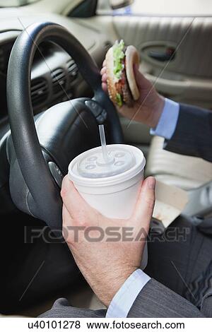 Stock Photo - USA, Illinois, Metamora, Man's hands holding burger and disposable cup with straw. Fotosearch