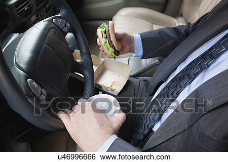 Stock Photograph - USA, Illinois, Metamora, Man's hands holding burger and disposable cup with straw. Fotosearch