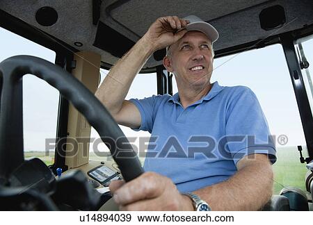 Stock Photo - USA, Illinois, Metamora, mature man driving tractor. Fotosearch