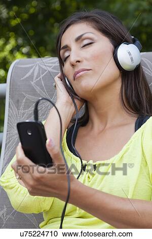 Stock Image - USA, Illinois, Metamora, mature woman listening music from smart phone. Fotosearch