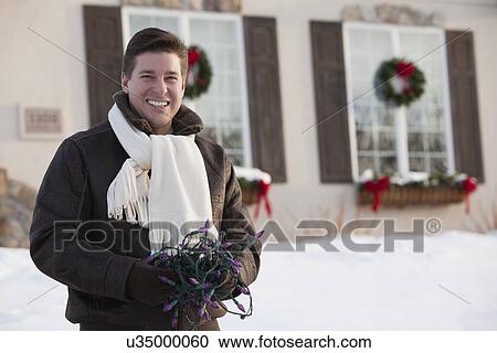 USA, Illinois, Metamora, mid adult man holding Christmas lights View Large Photo Image Stock Image - USA, Illinois, Metamora, mid adult man holding Christmas lights. Fotosearch