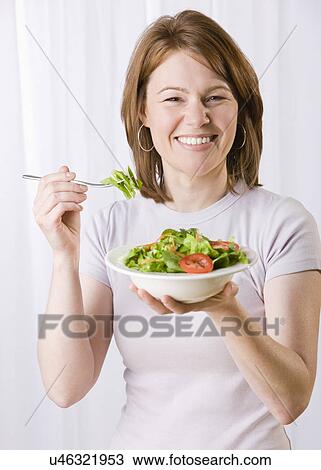 Stock Image - USA, Illinois, Metamora, mid adult woman eating salad. Fotosearch