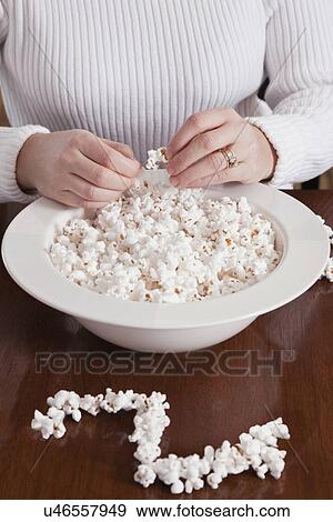 Stock Photo - USA, Illinois, Metamora, mid adult woman making popcorn Christmas ornament, mid-section. Fotosearch