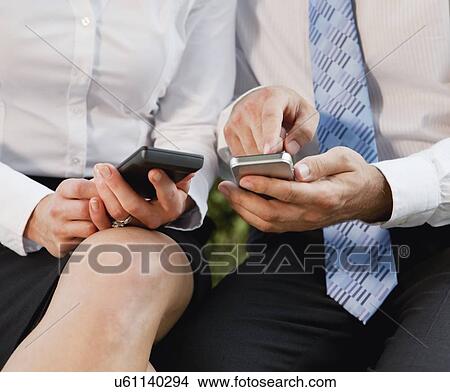 Picture - USA, Illinois, Metamora, midsection of business people using cell phones. Fotosearch