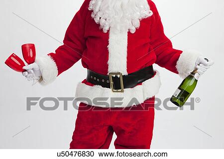 Stock Image - USA, Illinois, Metamora, Midsection of Santa Claus holding wineglasses and bottle. Fotosearch