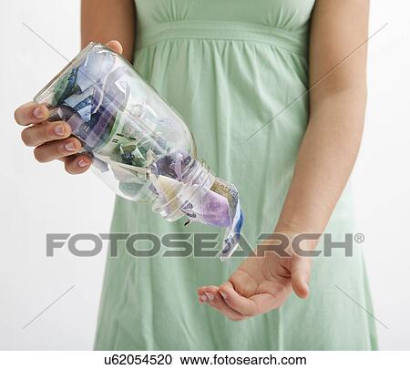Stock Image - USA, Illinois, Metamora, Midsection of woman emptying jar with money. Fotosearch