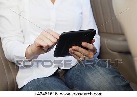 Stock Photograph - USA, Illinois, Metamora, midsection of woman reading e-book. Fotosearch
