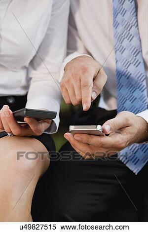 Stock Photography - USA, Illinois, Metamora, midsection of business people using cell phones. Fotosearch