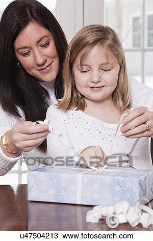 Stock Image - USA, Illinois, Metamora, mother and daughter wrapping Christmas present. Fotosearch