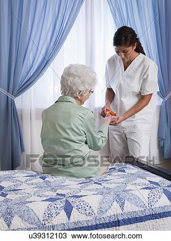 USA, Illinois, Metamora, Nurse giving pills to senior woman sitting on bed View Large Photo Image Stock Image - USA, Illinois, Metamora, Nurse giving pills to senior woman sitting on bed. Fotosearch