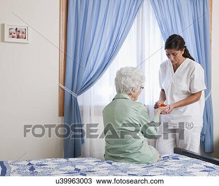 USA, Illinois, Metamora, Nurse giving pills to senior woman sitting on bed View Large Photo Image Stock Image - USA, Illinois, Metamora, Nurse giving pills to senior woman sitting on bed. Fotosearch