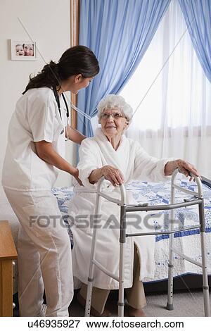 Stock Photo - USA, Illinois, Metamora, Nurse helping senior woman with walker. Fotosearch