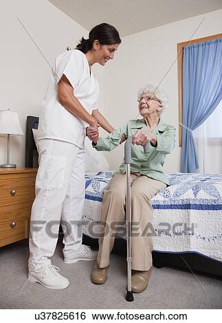 Stock Photograph - USA, Illinois, Metamora, Nurse helping senior woman with cane. Fotosearch