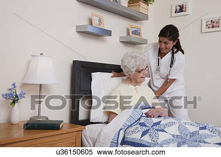 Stock Photography - USA, Illinois, Metamora, Nurse helping senior woman sitting in bed. Fotosearch