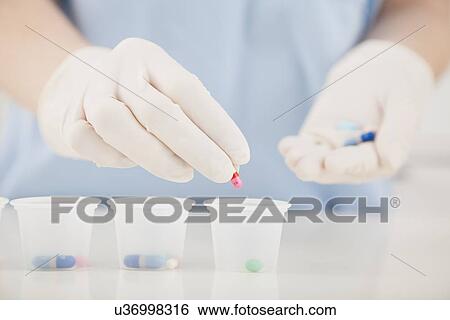 Stock Photograph - USA, Illinois, Metamora, Nurse's hands distributing medicines. Fotosearch
