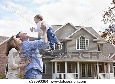 Picture - USA, Illinois, Metamora, parents playing with baby boy (12-17 months) in front of house. Fotosearch
