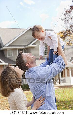 USA, Illinois, Metamora, parents playing with baby boy (12-17 months) in front of house View Large Photo Image Stock Photograph - USA, Illinois, Metamora, parents playing with baby boy (12-17 months) in front of house. Fotosearch