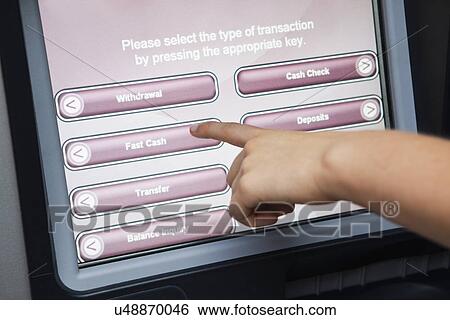 Stock Photograph - USA, Illinois, Metamora, Person using atm with touch-sensitive display. Fotosearch
