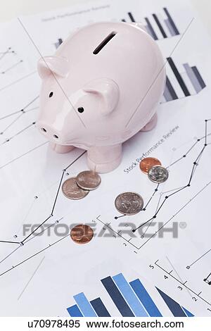 Stock Photography - USA, Illinois, Metamora, Piggy bank and coins on stock charts. Fotosearch
