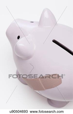 Stock Image - USA, Illinois, Metamora, Piggy bank with crack and bandage. Fotosearch