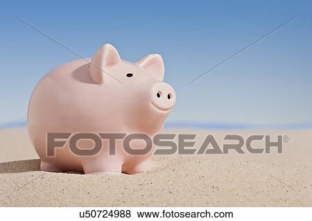 Stock Photo - USA, Illinois, Metamora, Piggybank on sand. Fotosearch
