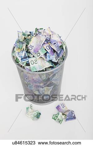Stock Image - USA, Illinois, Metamora, Pile of money in trashcan. Fotosearch