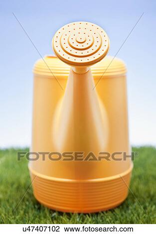 Stock Image - USA, Illinois, Metamora, Plastic watering can on lawn. Fotosearch