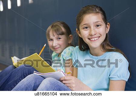 USA, Illinois, Metamora, Portrait of two girls (8-9) sitting at lockers in school corridor and doing homework View Large Photo Image Picture - USA, Illinois, Metamora, Portrait of two girls (8-9) sitting at lockers in school corridor and doing homework. Fotosearch