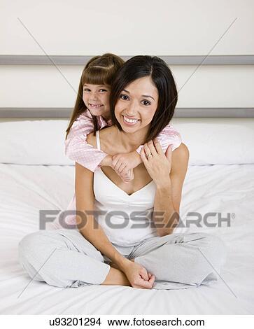 Picture - USA, Illinois, Metamora, Portrait of mother with daughter (6-7) on bed. Fotosearch