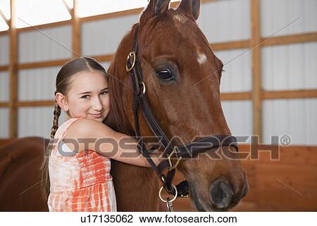 Stock Image - USA, Illinois, Metamora, Portrait of girl (10-11) embracing horse. Fotosearch