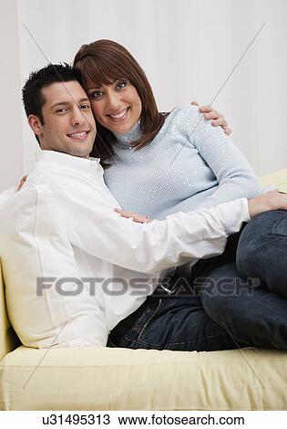 Stock Image - USA, Illinois, Metamora, Portrait of Couple embracing on sofa. Fotosearch