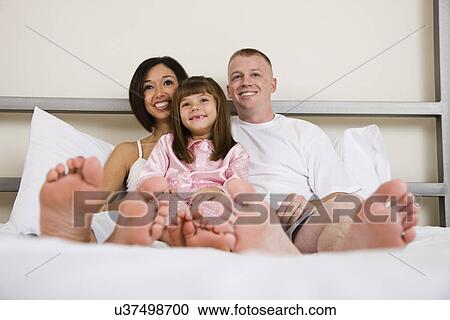 USA, Illinois, Metamora, Portrait of parents with daughter (6-7) on bed View Large Photo Image Stock Image - USA, Illinois, Metamora, Portrait of parents with daughter (6-7) on bed. Fotosearch