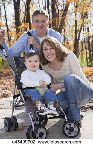 Stock Image - USA, Illinois, Metamora, portrait of parents with baby boy (12-17 months) in stroller. Fotosearch