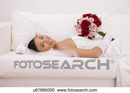 USA, Illinois, Metamora, Portrait of bride relaxing on sofa with bouquet View Large Photo Image Stock Image - USA, Illinois, Metamora, Portrait of bride relaxing on sofa with bouquet. Fotosearch
