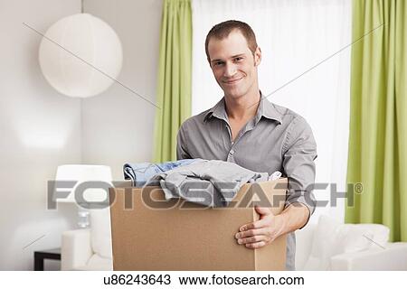 USA, Illinois, Metamora, Portrait of smiling man carrying cardboard box with clothes View Large Photo Image Stock Image - USA, Illinois, Metamora, Portrait of smiling man carrying cardboard box with clothes. Fotosearch