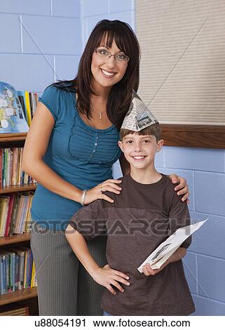 Stock Image - USA, Illinois, Metamora, Portrait of school boy (8-9) with teacher in classroom. Fotosearch