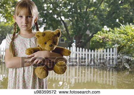 USA, Illinois, Metamora, Portrait of girl (8-9) holding teddy in flooded yard View Large Photo Image Stock Image - USA, Illinois, Metamora, Portrait of girl (8-9) holding teddy in flooded yard. Fotosearch