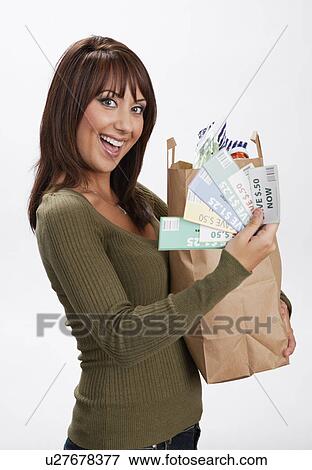 Stock Photo - USA, Illinois, Metamora, Portrait of woman holding shopping bag and coupons. Fotosearch