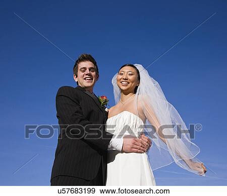 Stock Photo - USA, Illinois, Metamora, Portrait of bride and groom embracing. Fotosearch