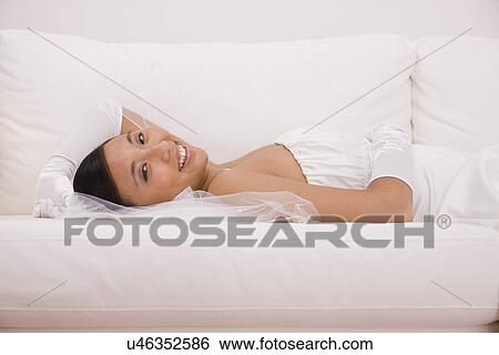 Stock Photograph - USA, Illinois, Metamora, Portrait of bride relaxing on sofa. Fotosearch