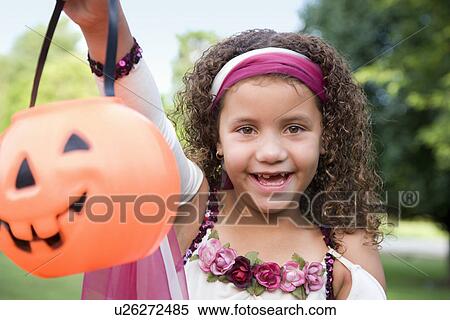 Stock Photography - USA, Illinois, Metamora, Portrait of girl (8-9) in Halloween costume holding bag. Fotosearch