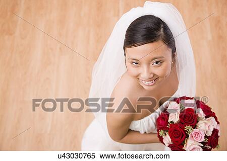 USA, Illinois, Metamora, Portrait of bride holding bouquet indoors View Large Photo Image Stock Photography - USA, Illinois, Metamora, Portrait of bride holding bouquet indoors. Fotosearch